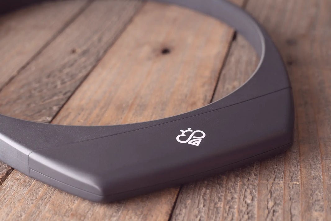 Matte black Hapbee neckband wellness device on wood, showing the curved ergonomic shape and white Hapbee logo on the side.