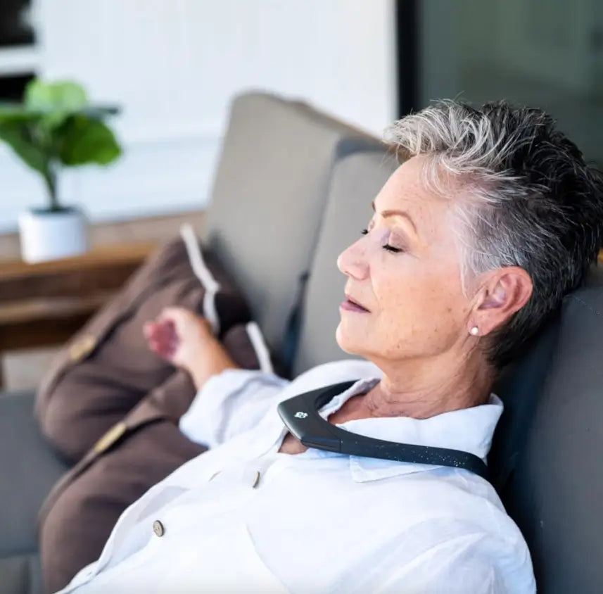 Woman relaxing on a couch while wearing the Hapbee Neckband